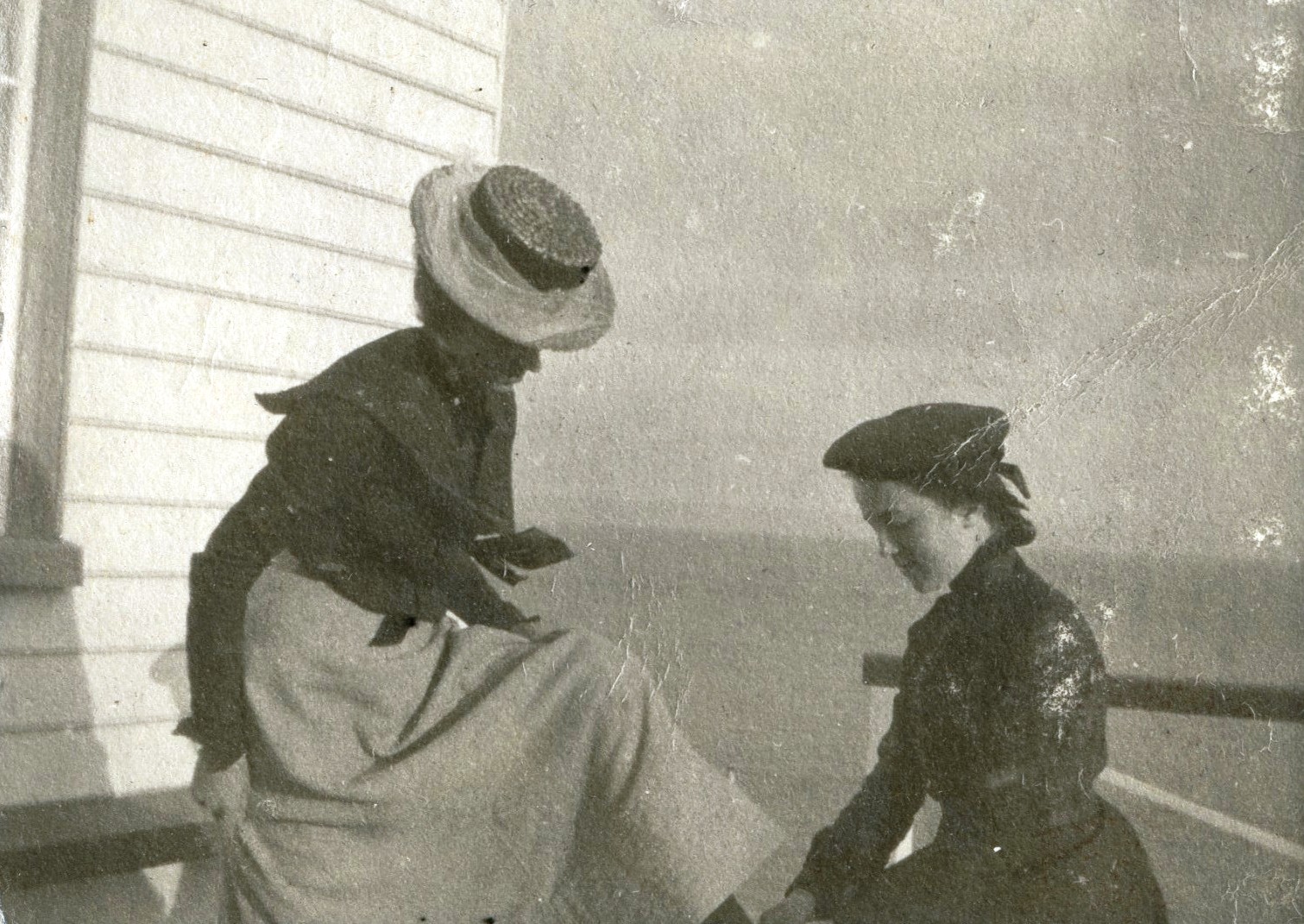 A young woman laces the shoes of a seated woman.