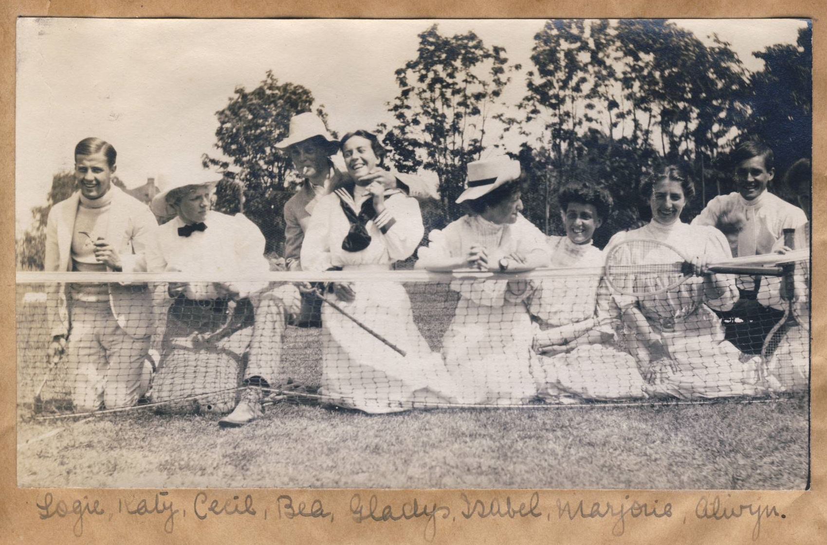 Tennis players in dresses, jackets and shirts sitting near the net.