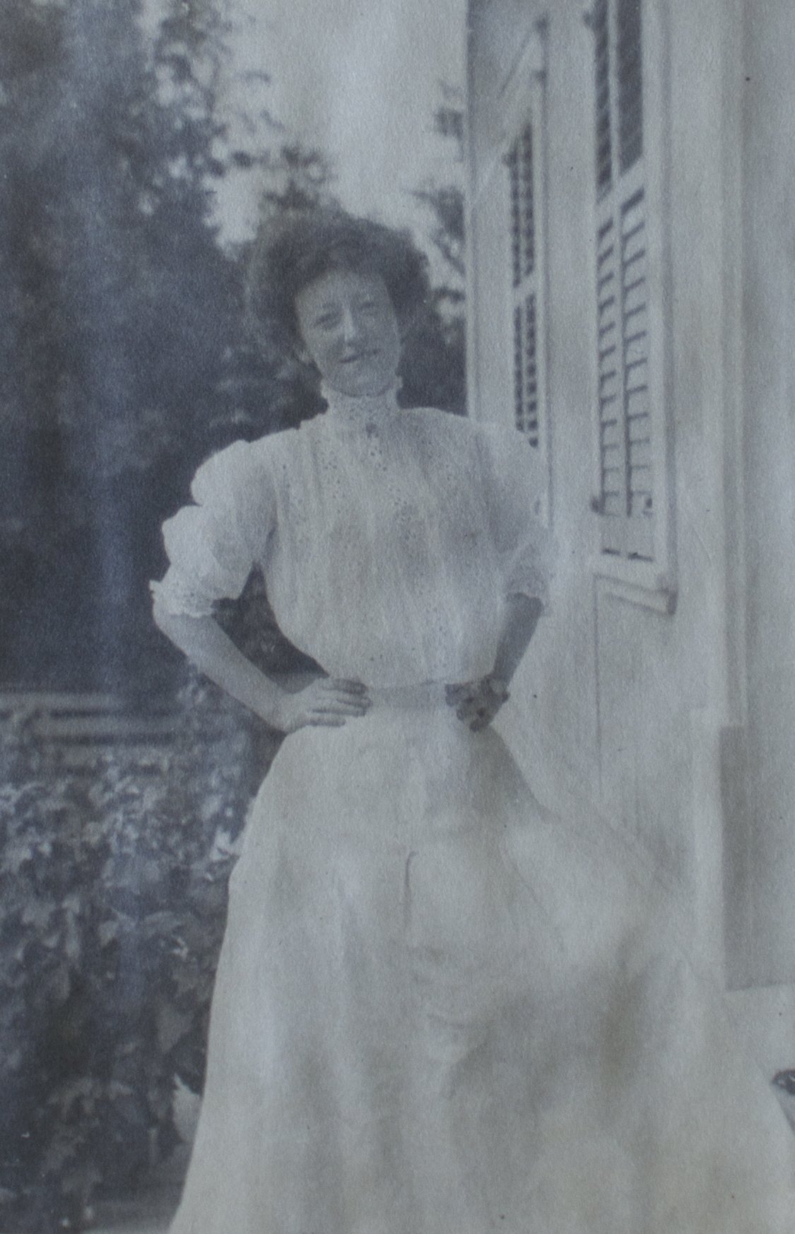 A woman wearing a long white dress with a high neckline; she is quite petite.