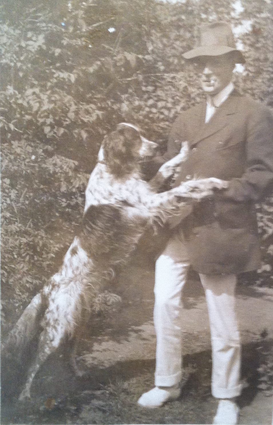 A dog standing on hind legs, front paws on a properly dressed man.