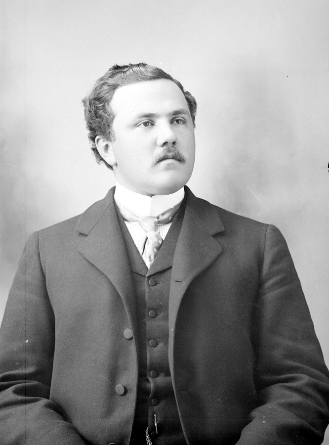 Portrait of a man sporting a mustache, coat and tie.