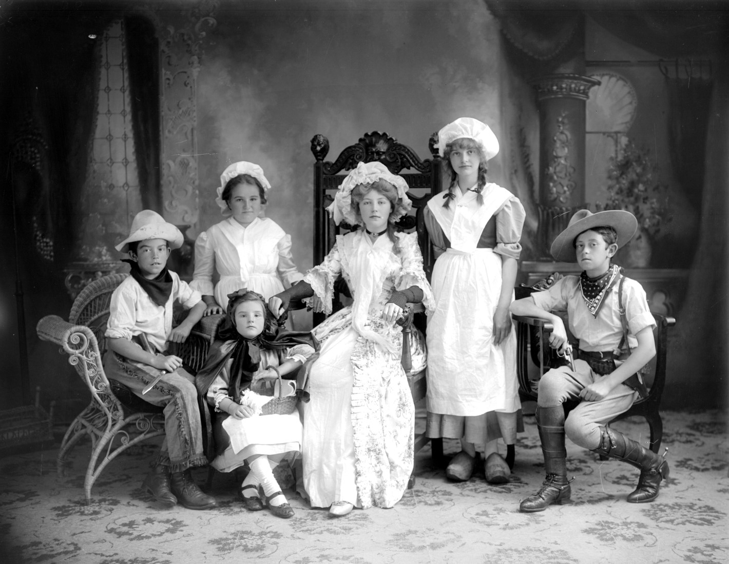Six children in costumes posing proudly in a photographer’s studio.