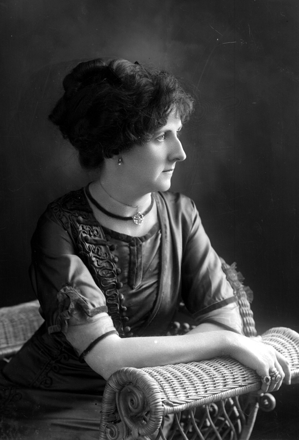 Portrait of a distinguished woman sitting in a wicker chair.