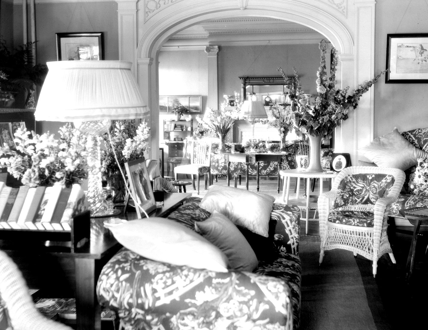The bright living room of a summer home decorated with bouquets of flowers.