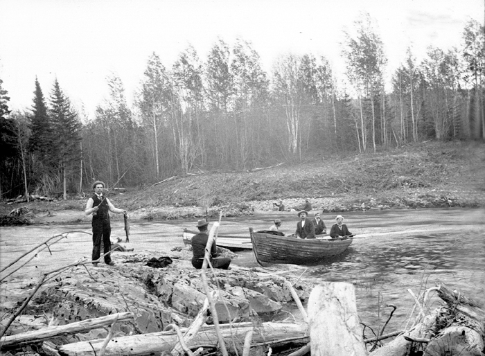 Des hommes pêchent sur une rivière : certains sont en chaloupe, d’autres sur la rive.