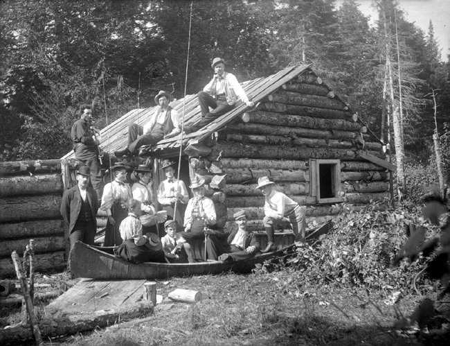 Une famille se tient devant un camp de bois rond.