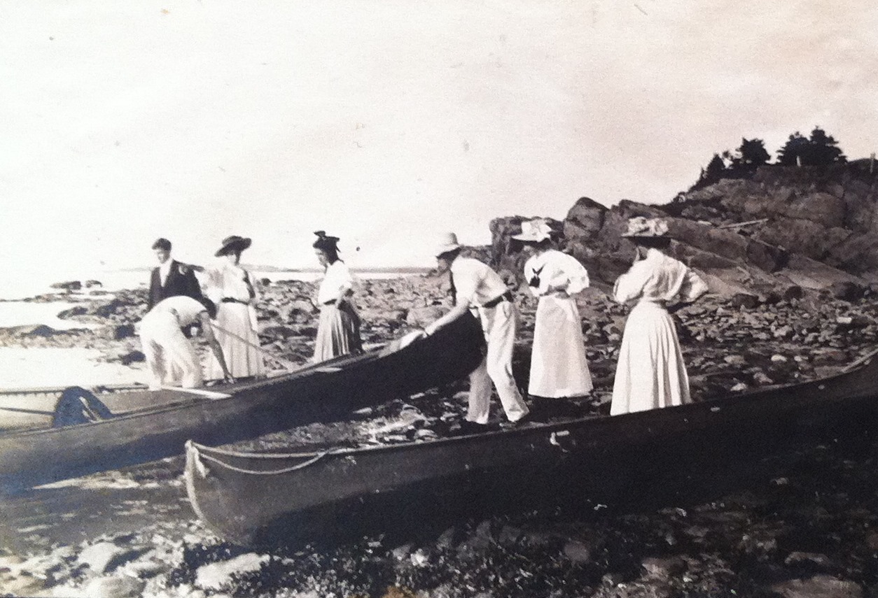 A small group getting ready for a canoe trip. Almost all are dressed in white or very pale colours.