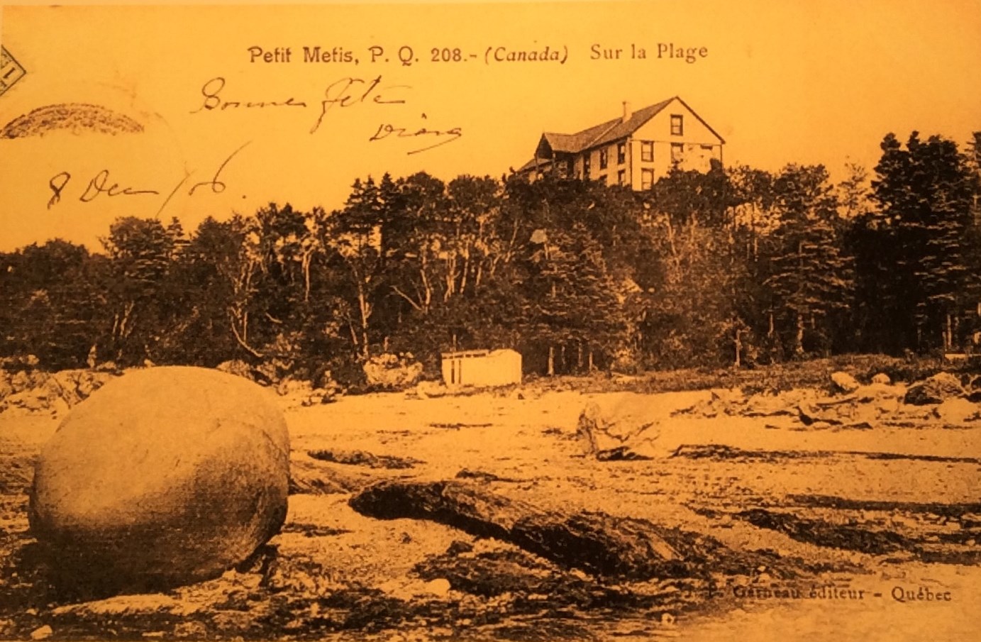 Un hôtel domine une falaise; en contrebas se trouve une plage parsemée de rochers et de cailloux.