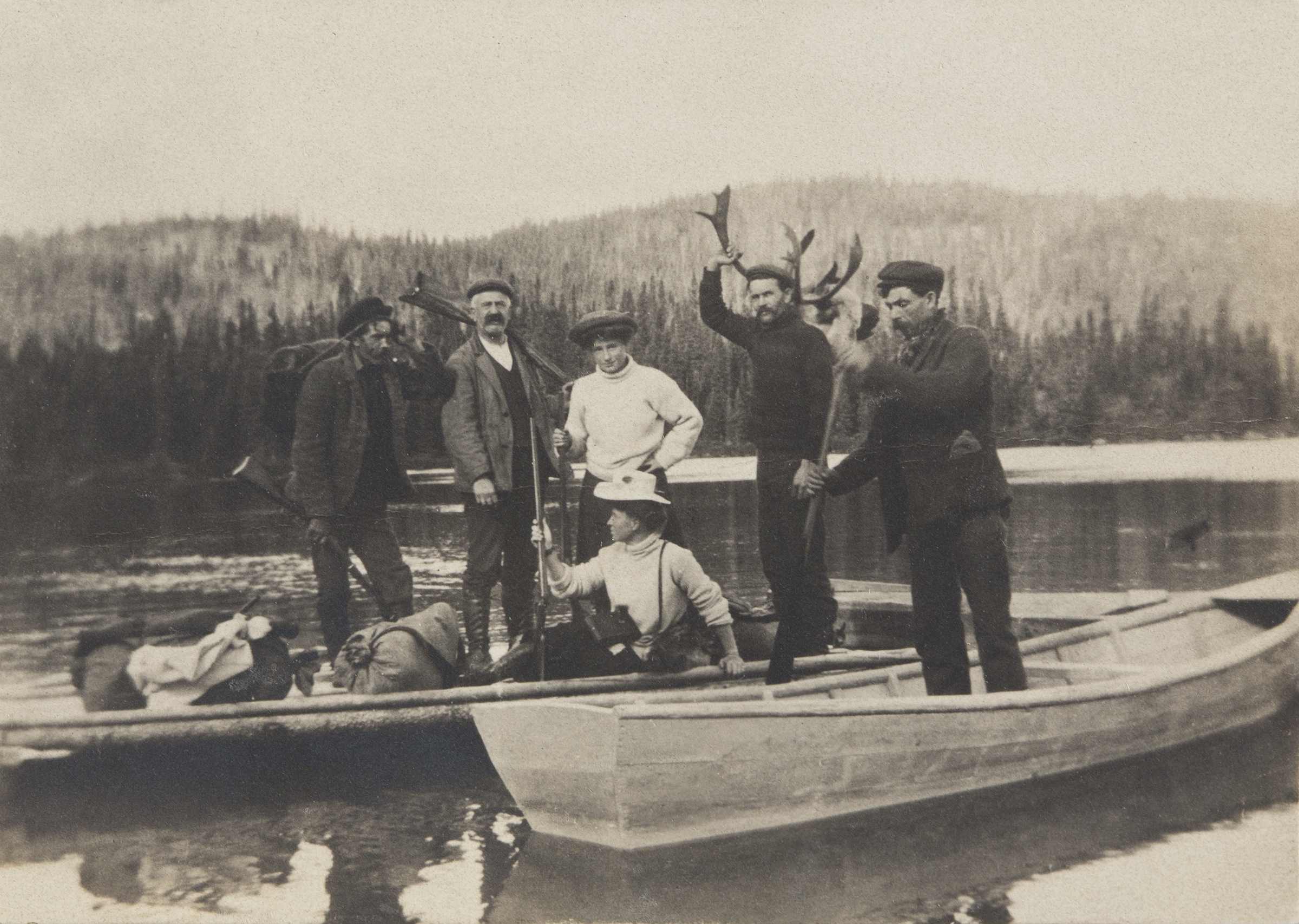 A small group of men and women in canoes, near a wharf.