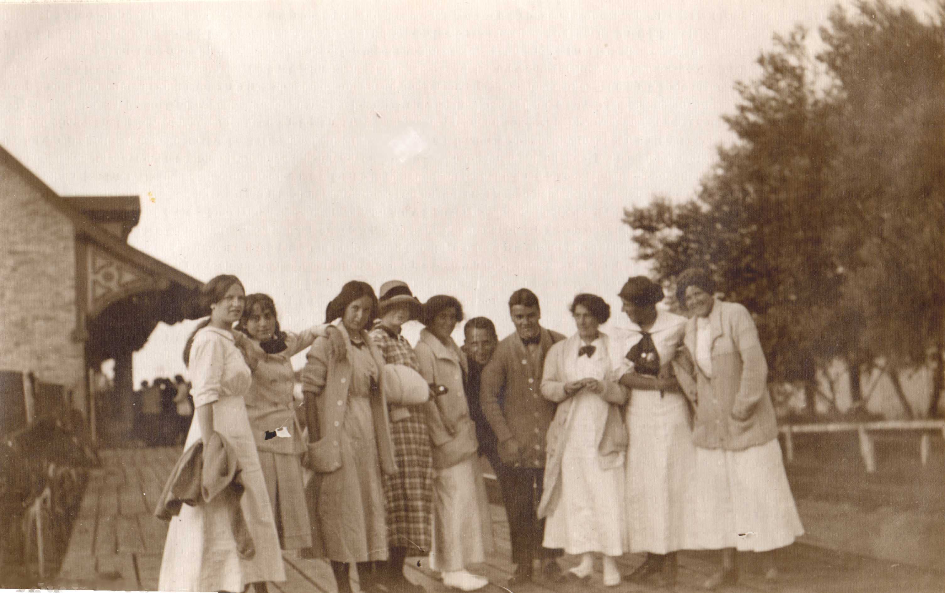 Young people waiting on a boardwalk near an old building.