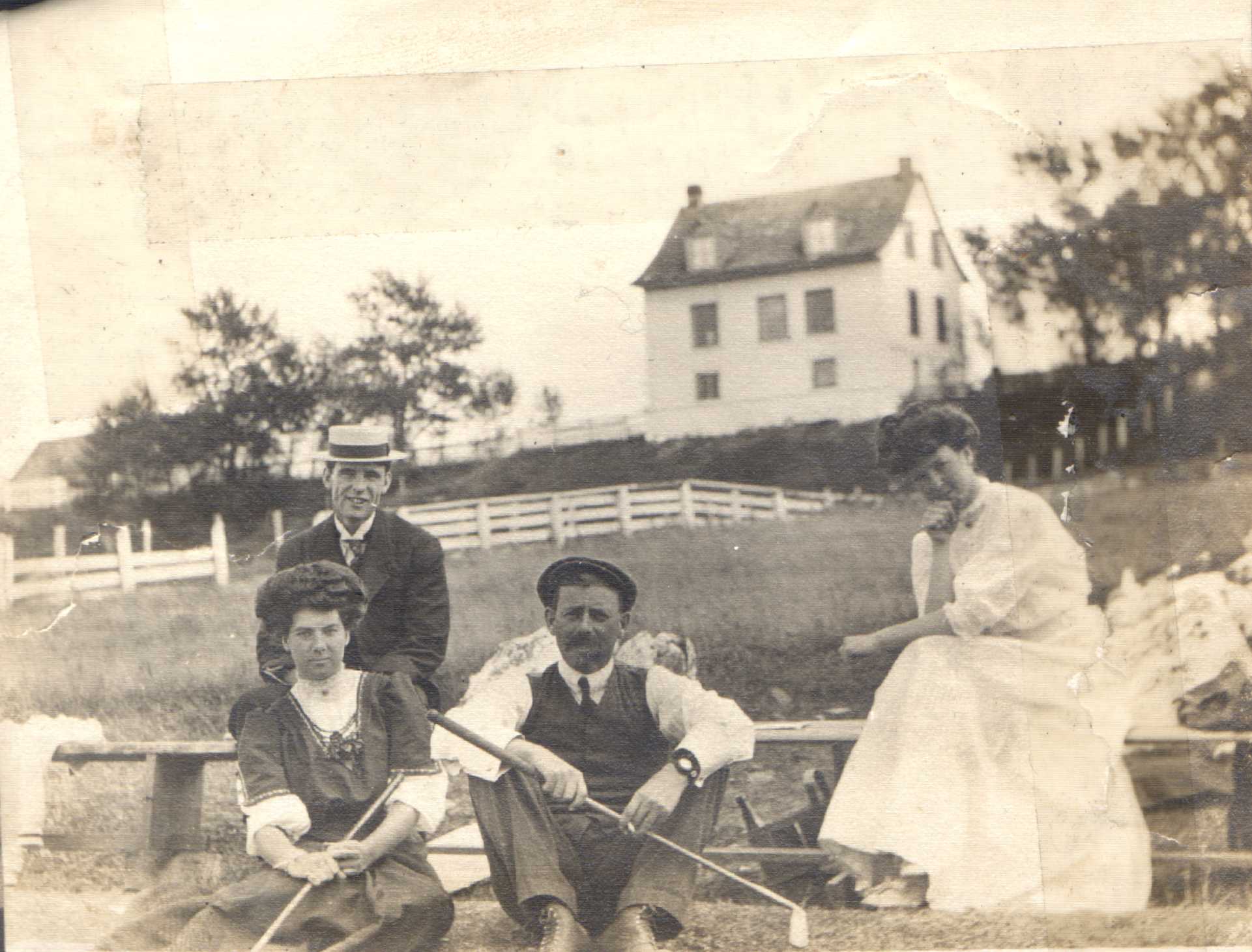 A photograph shows two men and two women sitting. Two of them are holding golf clubs.