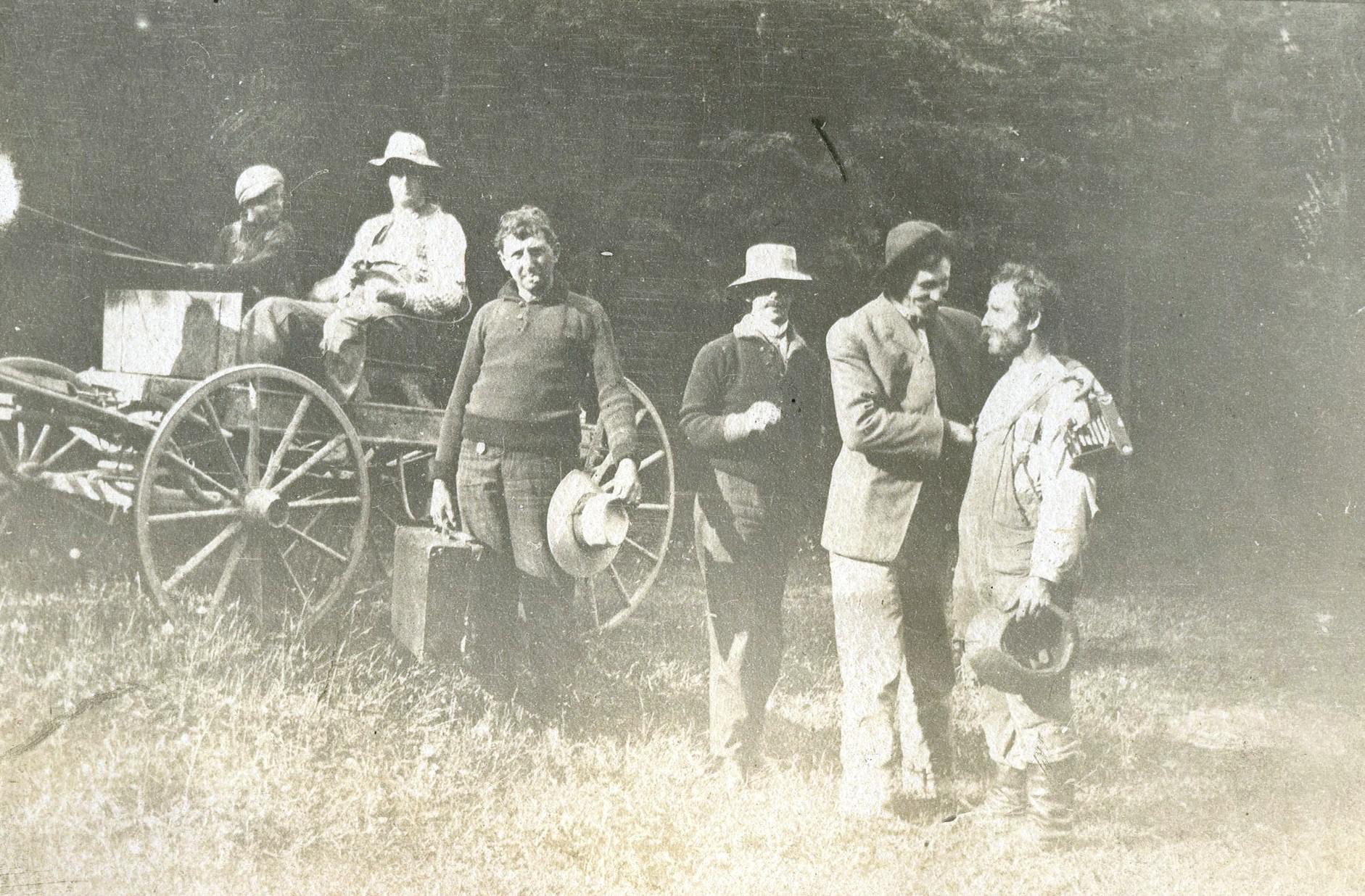 Men standing near a horse-drawn carriage meet a man in working clothes.