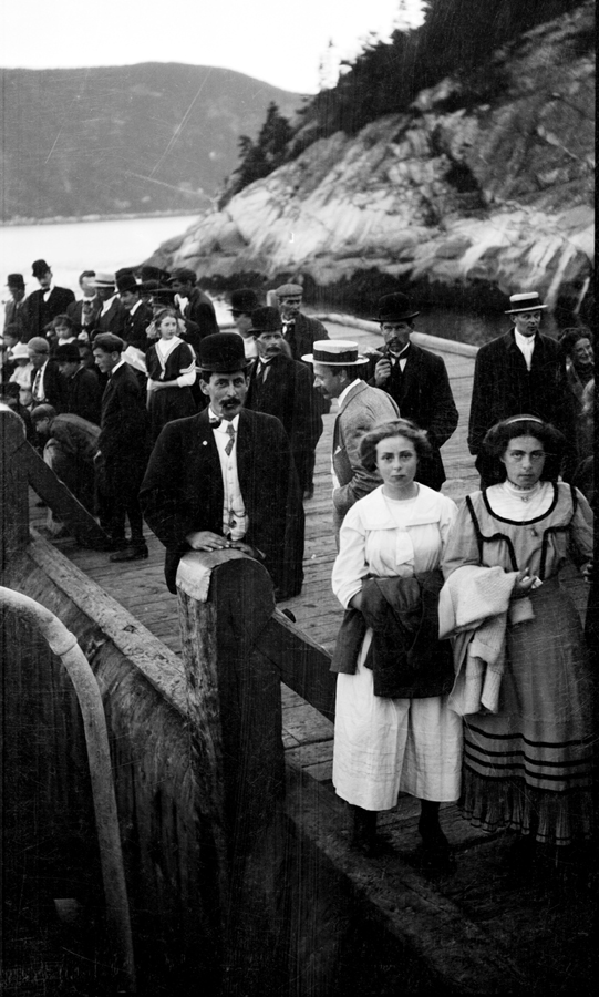 People standing on a wharf against a backdrop of mountains