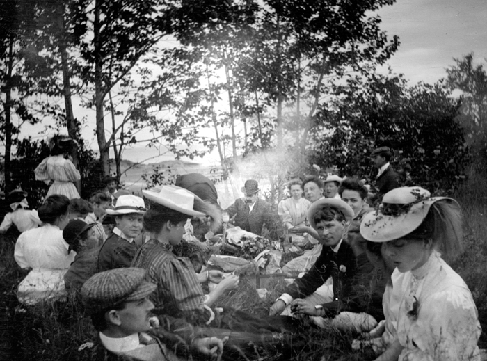 Des personnes sont assises dans l’herbe à l’occasion d’un pique-nique.