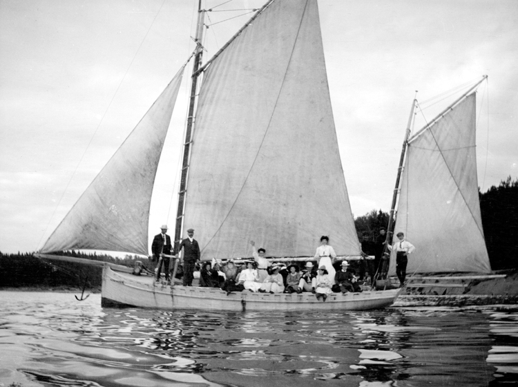 A sailboat floating on the water, filled with passengers.