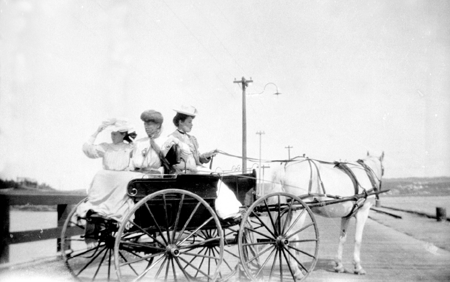 Trois dames dans un boghei sur le quai.