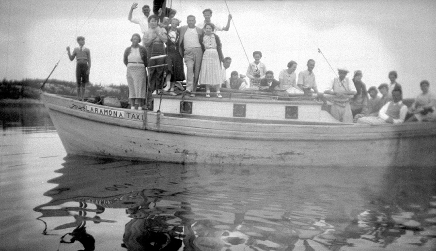 Des personnes vêtues assez simplement sont à bord d’un petit bateau.