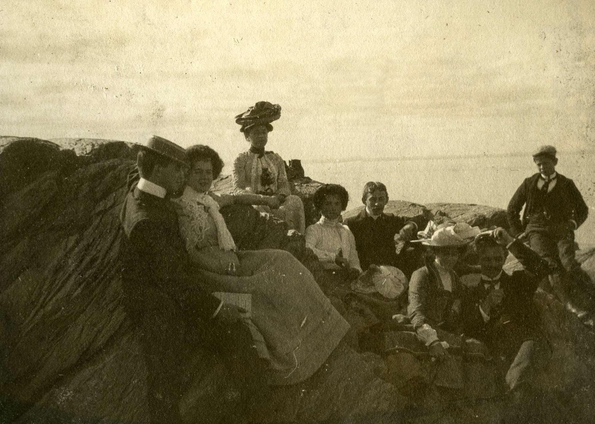 Young couples sitting on a rocky water’s edge, accompanied by a woman and young man.