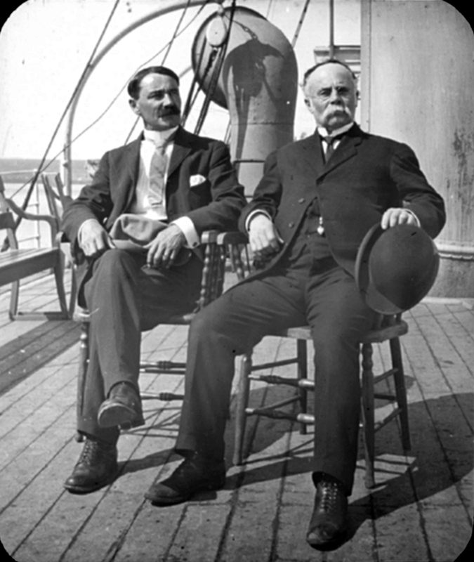 Two men sitting on chairs on the deck of a boat.