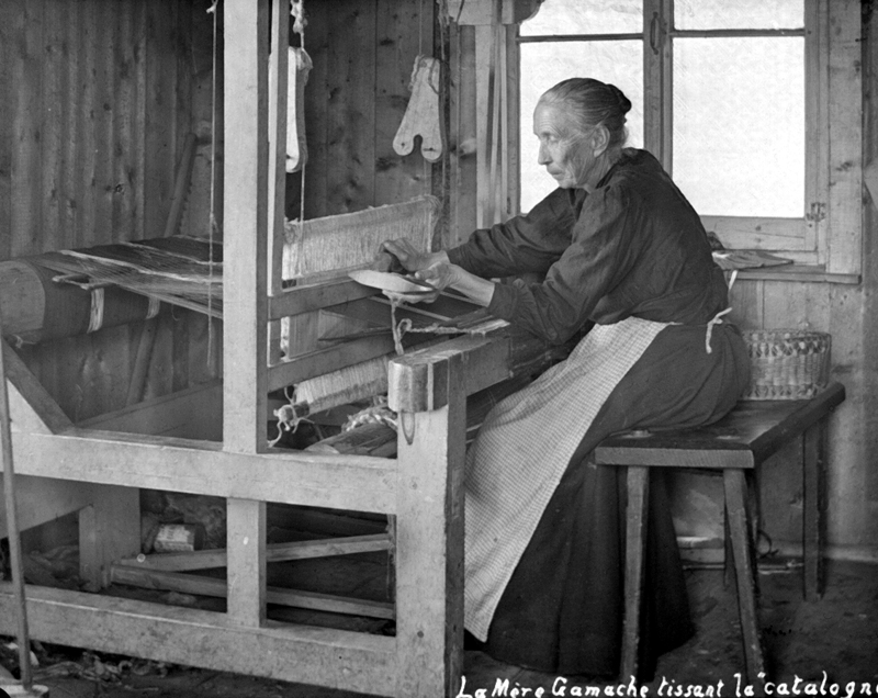 An old woman weaving at her loom.