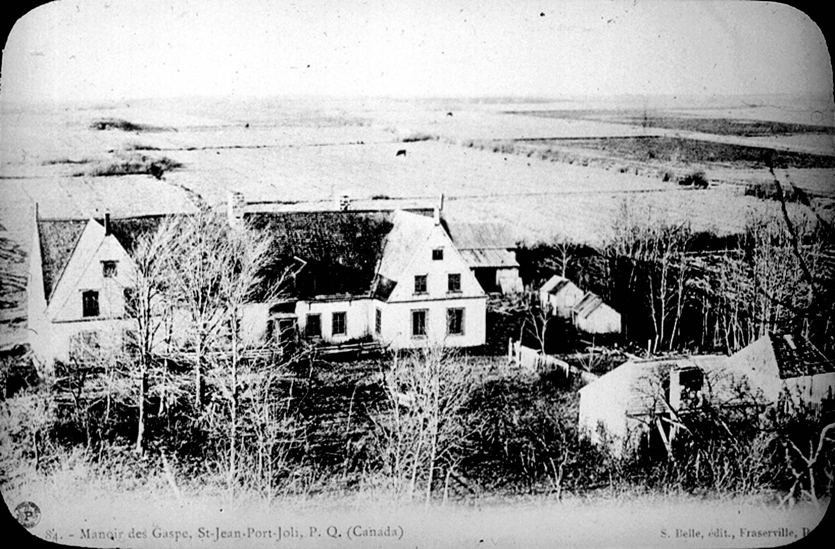 An old post card showing an impressively large residence and its out-buildings with large pastures in the background.