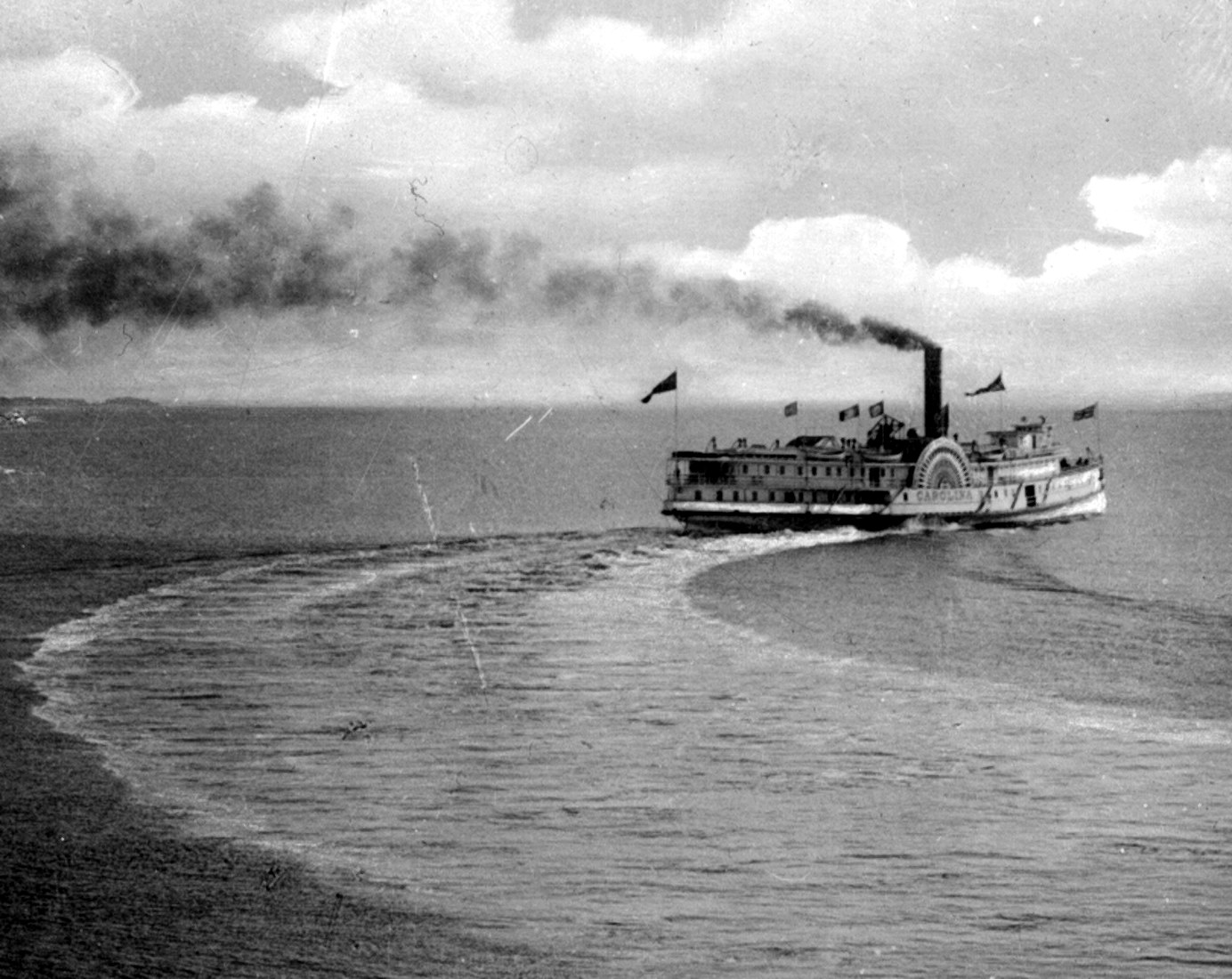 A cruise ship maneuvering, black smoke rising out of its chimney.