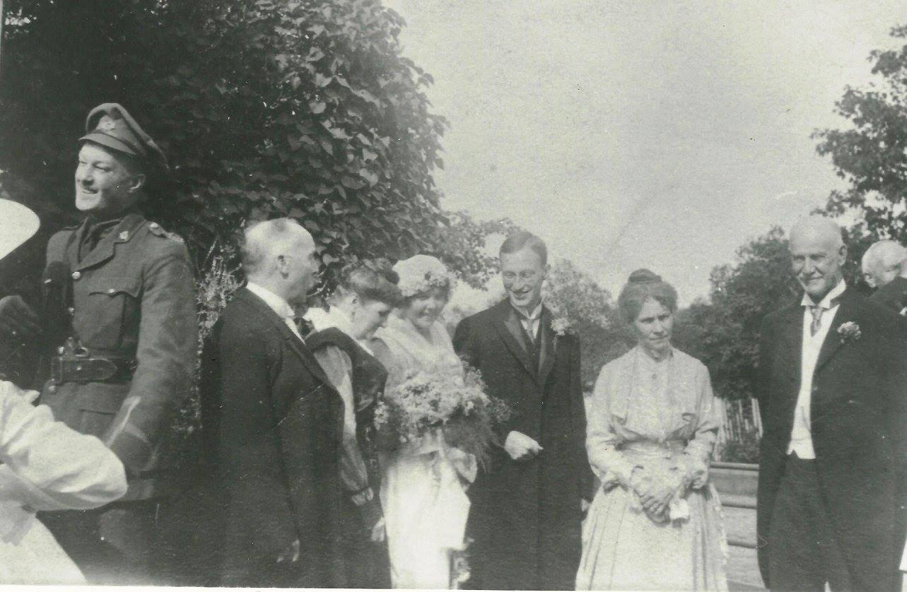 A photograph of newlyweds with their respective parents and other guests, outdoors.