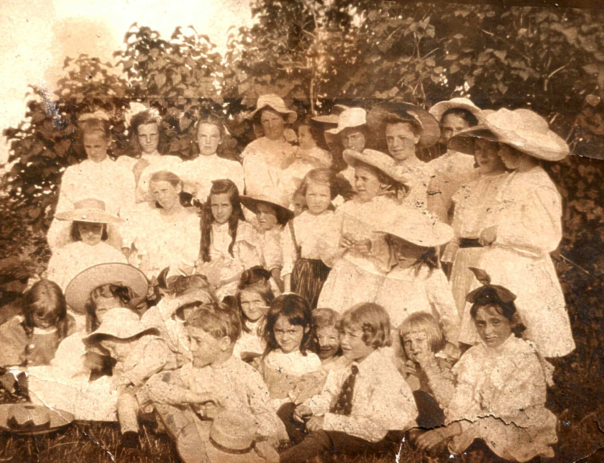 About thirty summer people of all ages, mainly young girls, posing by lilacs.