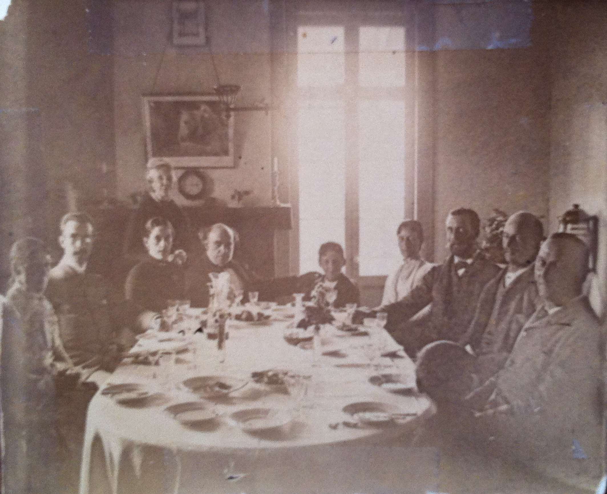 A dozen guests are seated at a dining table.