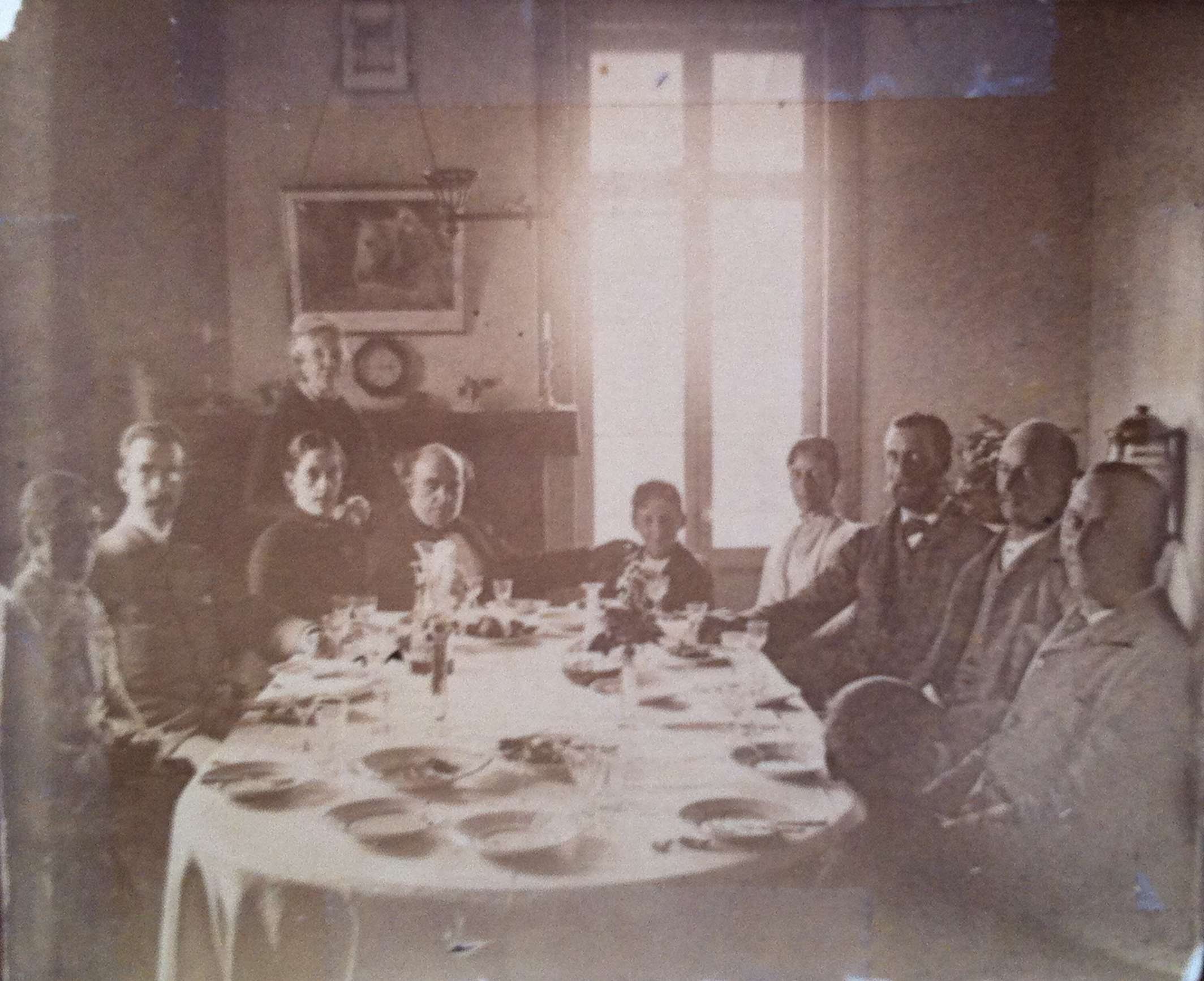 Une dizaine de convives sont attablés dans une salle à manger.