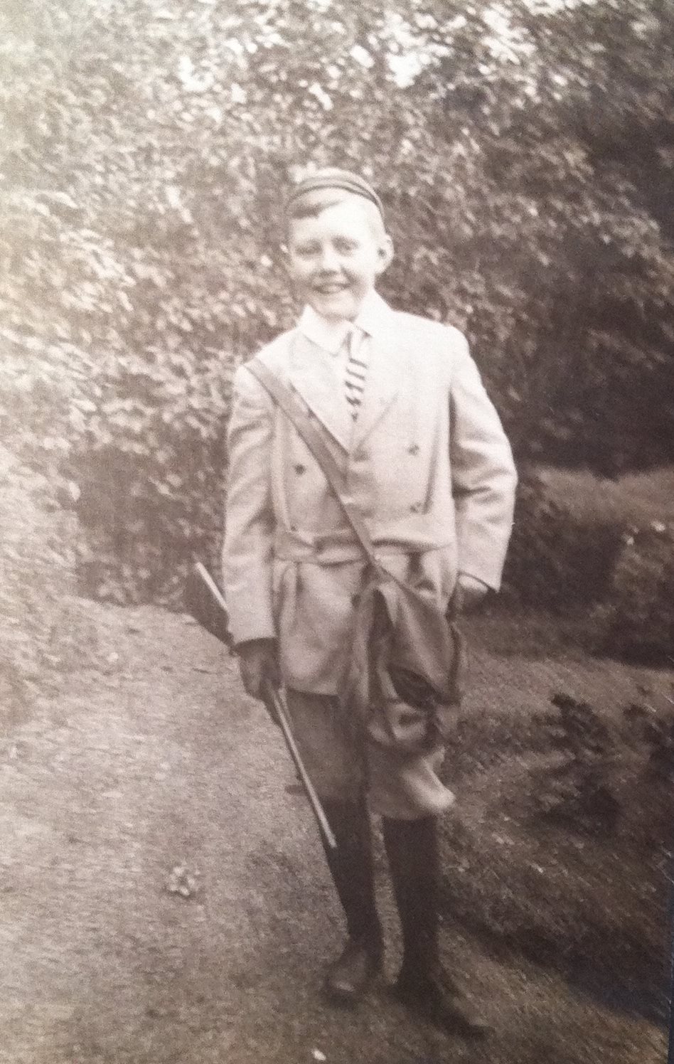 Un enfant pose fièrement en habit de chasse très stylé, carabine à la main.