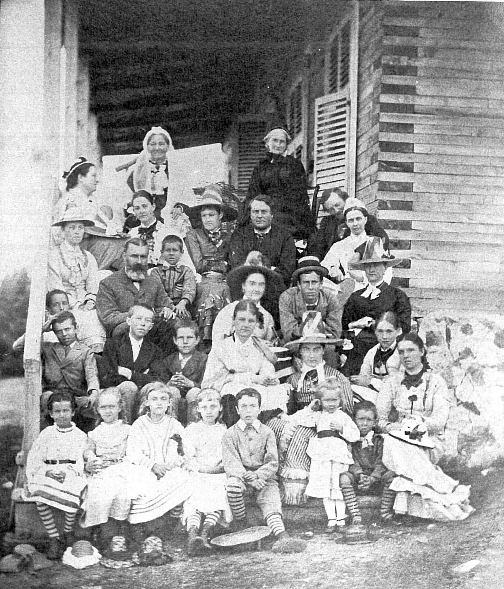 A photograph of four men and three women in front of a log cabin at a hunting-and-fishing camp.
