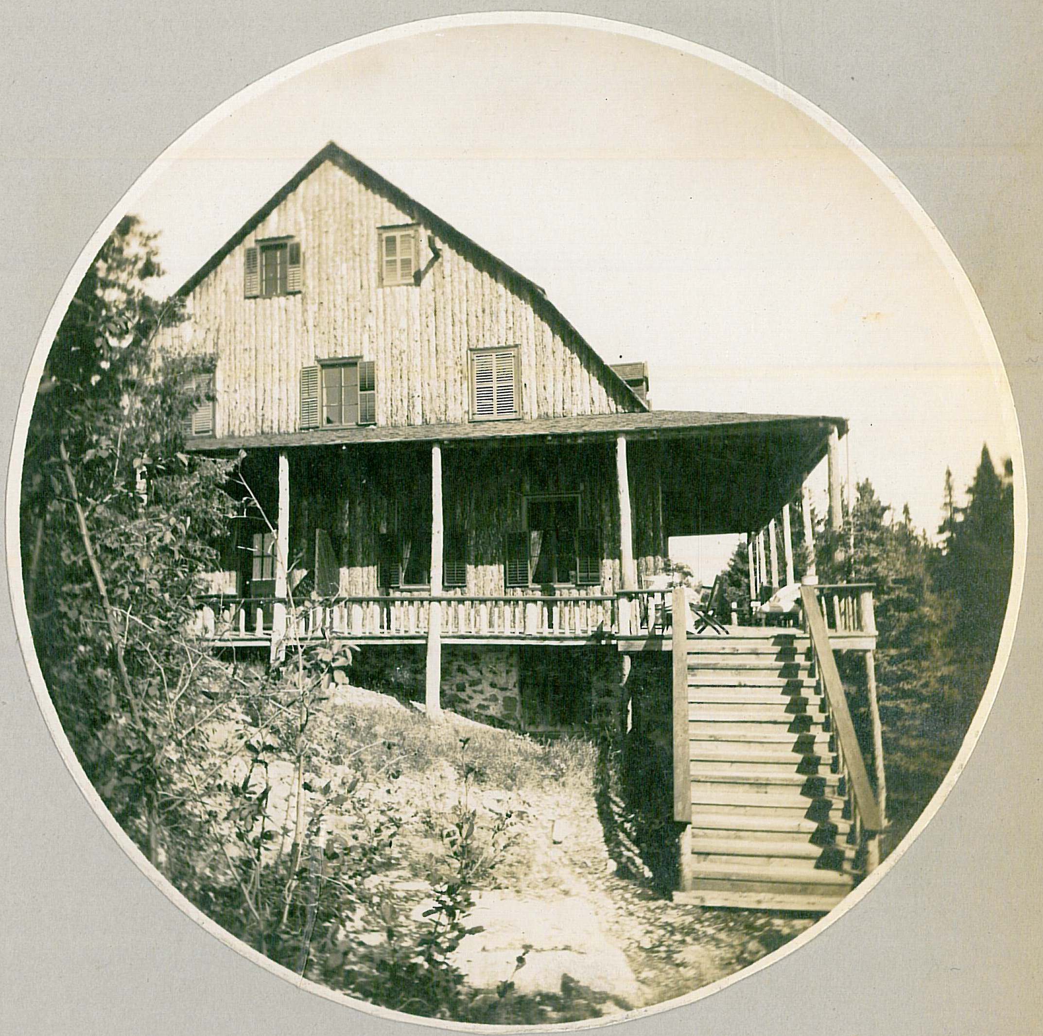 Grande résidence au revêtement extérieur en planches, construite au flanc d'un rocher et ceinturée par une galerie couverte.