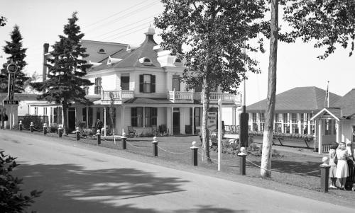 black and white photograph of an inn and a pavilion with many windows.