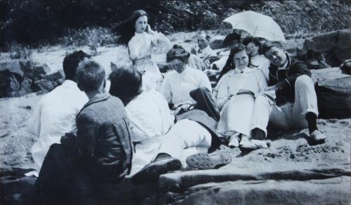 Une douzaine d'adolescents, habillés avec des vêtements longs et propres, se reposent sur une plage.
