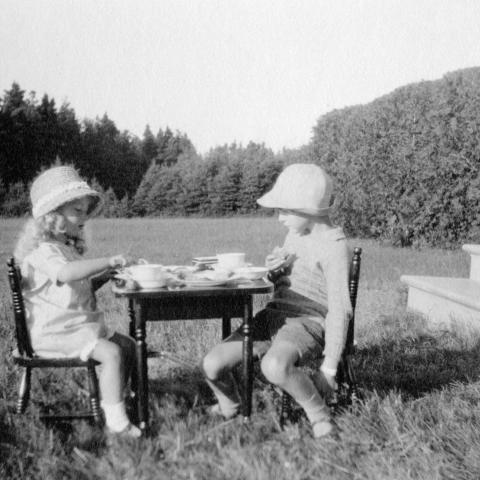 Two children are serving themselves at a little table set up on the lawn.