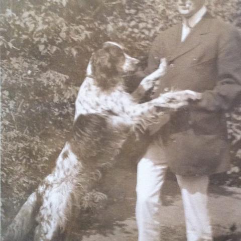 A dog standing on hind legs, front paws on a properly dressed man.