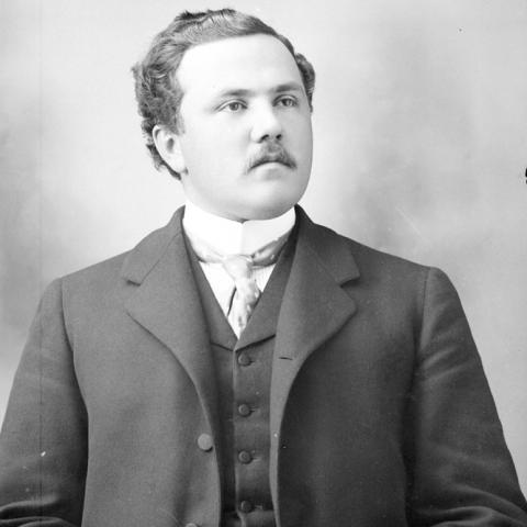 Portrait of a man sporting a mustache, coat and tie.