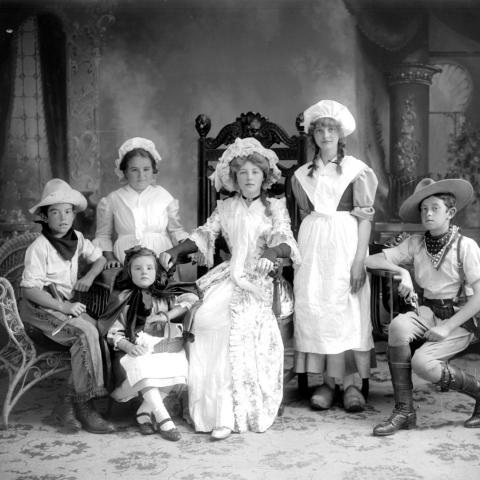Six enfants déguisés posent fièrement dans un studio de photographie.