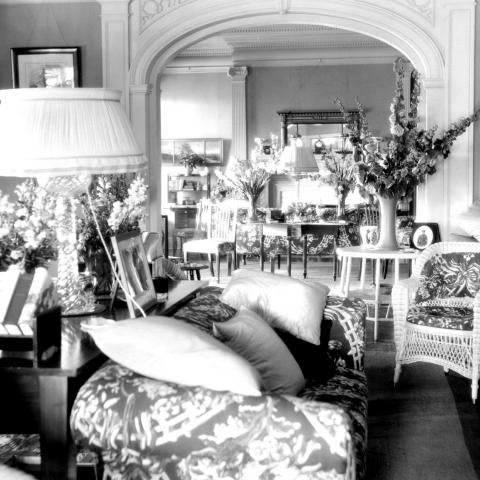 The bright living room of a summer home decorated with bouquets of flowers.