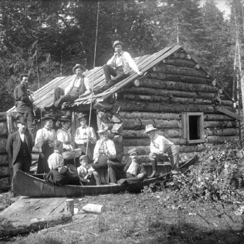 Une famille se tient devant un camp de bois rond.