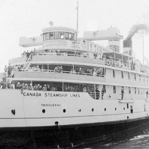A cruise steamer with passengers on deck.