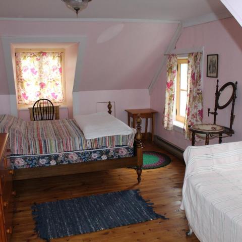 A colour photograph of a small bedroom with old-fashioned furnishings