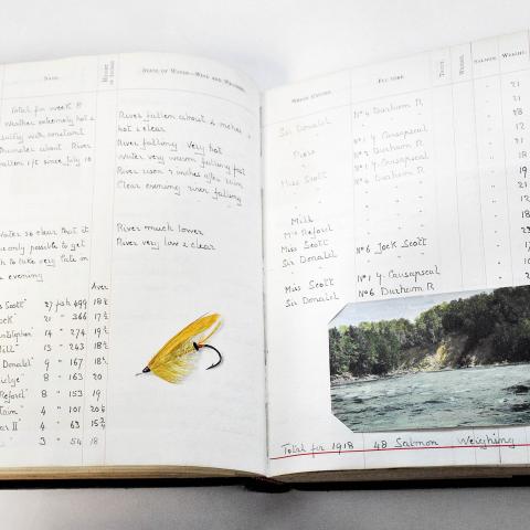 A handwritten notebook with a fly-fishing lure glued in and a colour illustration.