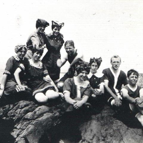 A photograph shows nine young people on a rock off the main shore of the St. Lawrence. They wear bathing suits that were stylish