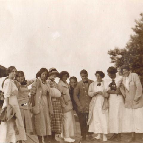 Young people waiting on a boardwalk near an old building.