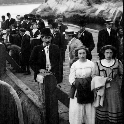 People standing on a wharf against a backdrop of mountains