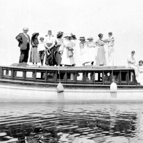 A dozen people posing on the roof of a motorized yacht.