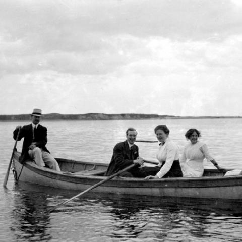 A small group in a rowboat, on the water.