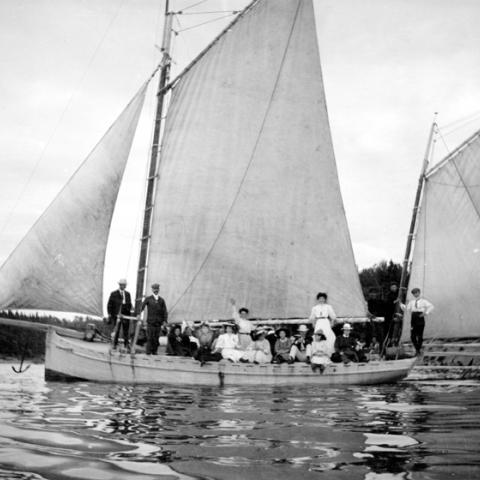A sailboat floating on the water, filled with passengers.